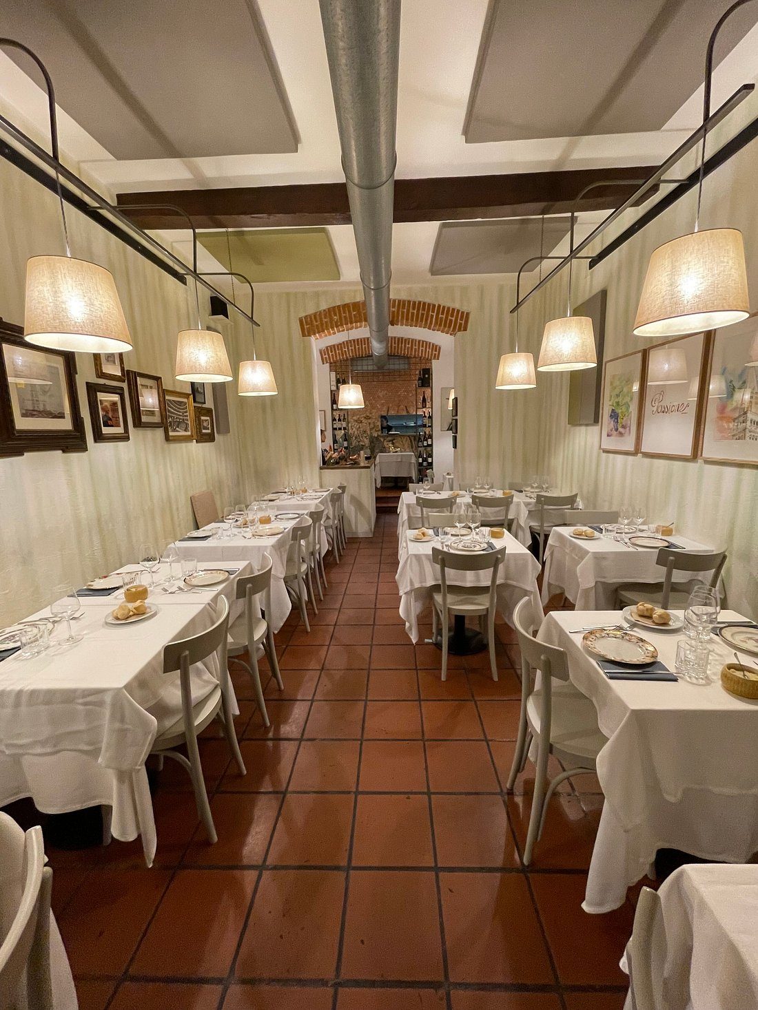 Tavoli apparecchiati sotto le lampade della sala